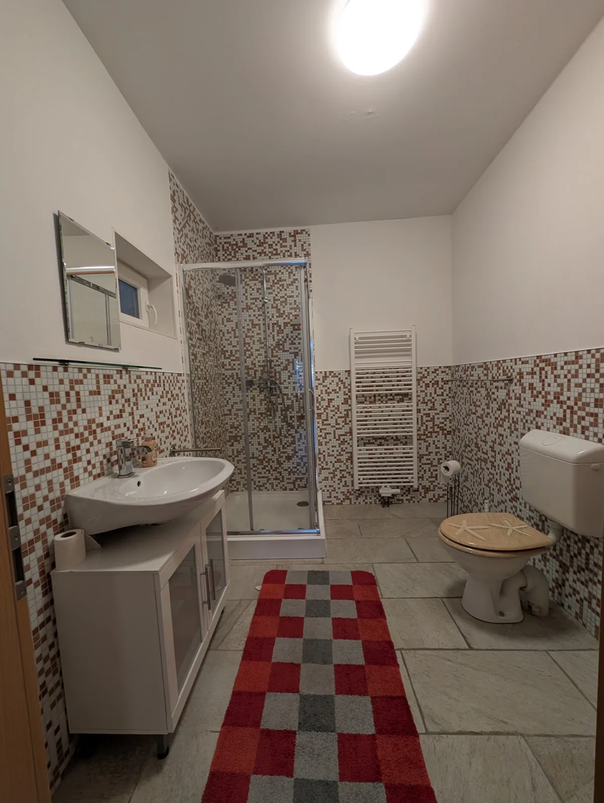 Eigenes Bad der Wohnung Eiche in Erkner mit Dusche, Waschbecken und Handtuchheizkörper