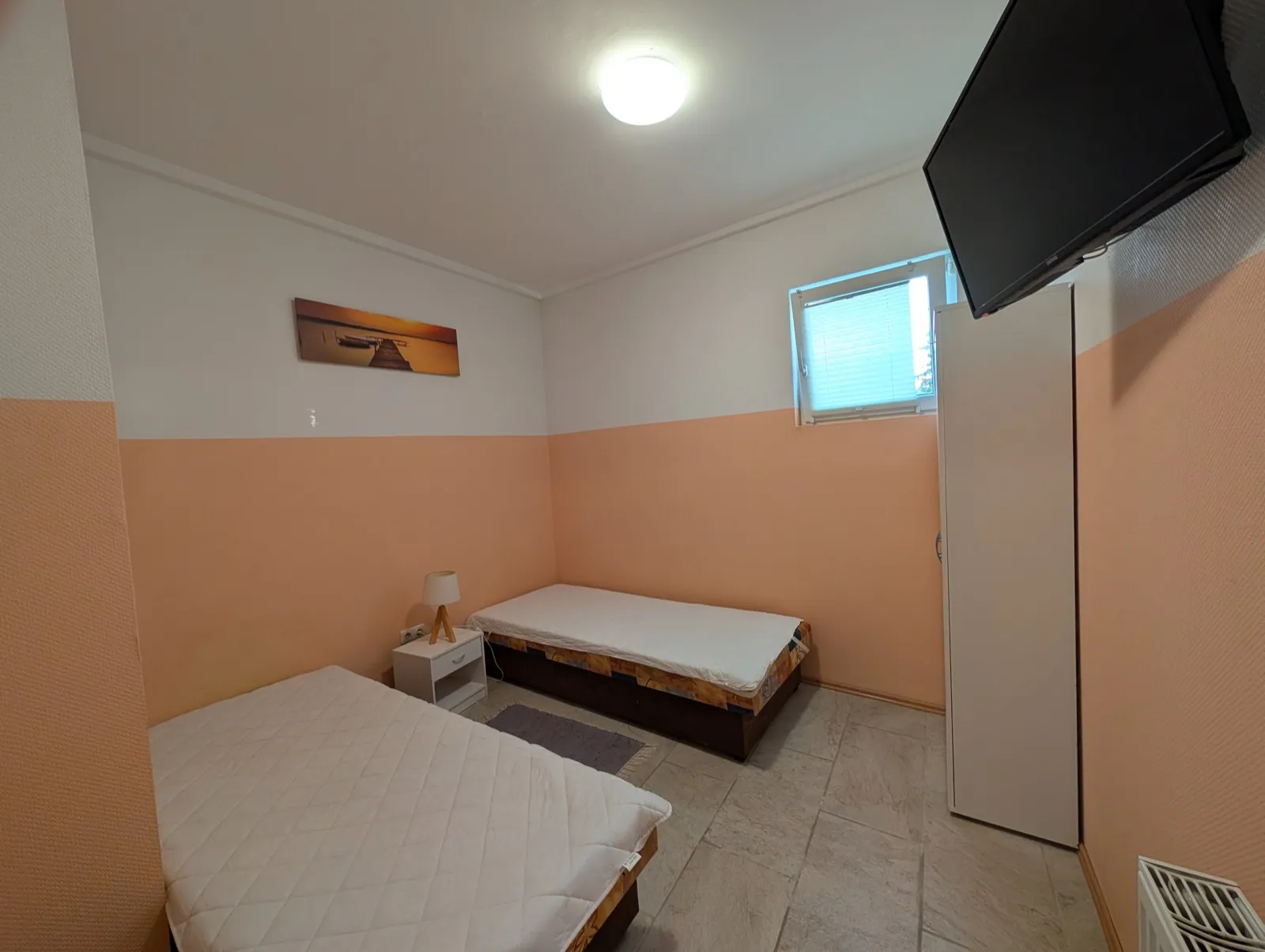 Erstes Schlafzimmer der Wohnung Eiche in Erkner mit zwei Einzelbetten, Fernseher und Kleiderschrank